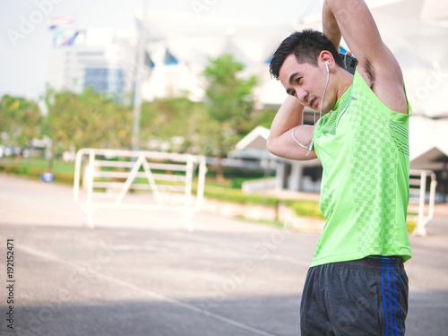 Young asian man runner doing stretching exercise, preparing for morning workout in the park