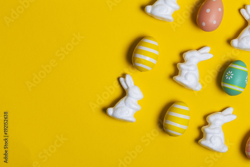 Easter bunny rabbit and eggs on a bright yellow background