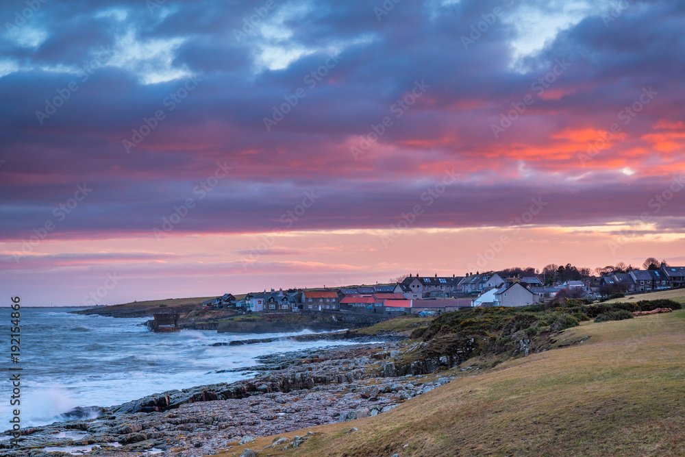 Sunset over Craster Village / Craster is a small fishing village on the Northumberland coast, with a small harbour and views to the ruins of Dunstanburgh Castle