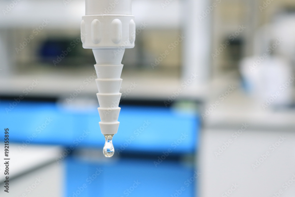 Closeup plastic tap with water drop to sink in chemical laboratory class blurred background. Closeup plastic tap with water drop to sink in chemical laboratory class blurred background.