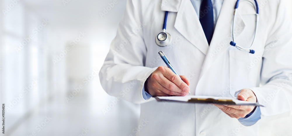 Male doctor writes notes on the clipboard in the hospital - obrazy, fototapety, plakaty 