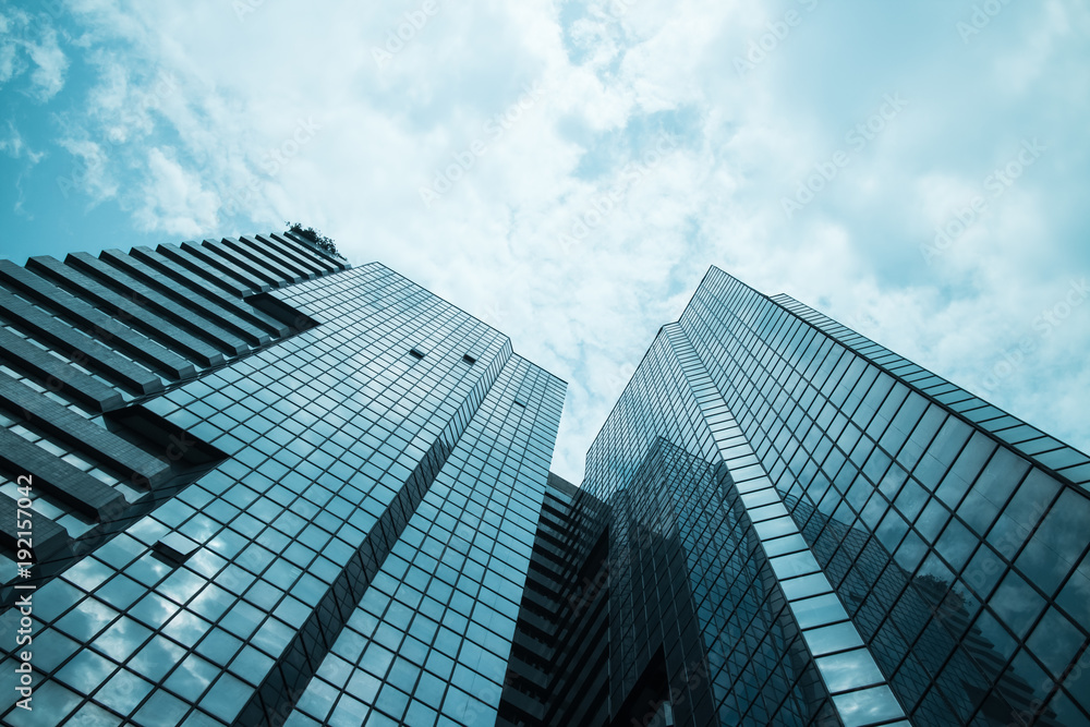 glass reflective office buildings against blue sky with clouds and sun light. glass reflective office buildings against blue sky with clouds and sun light.