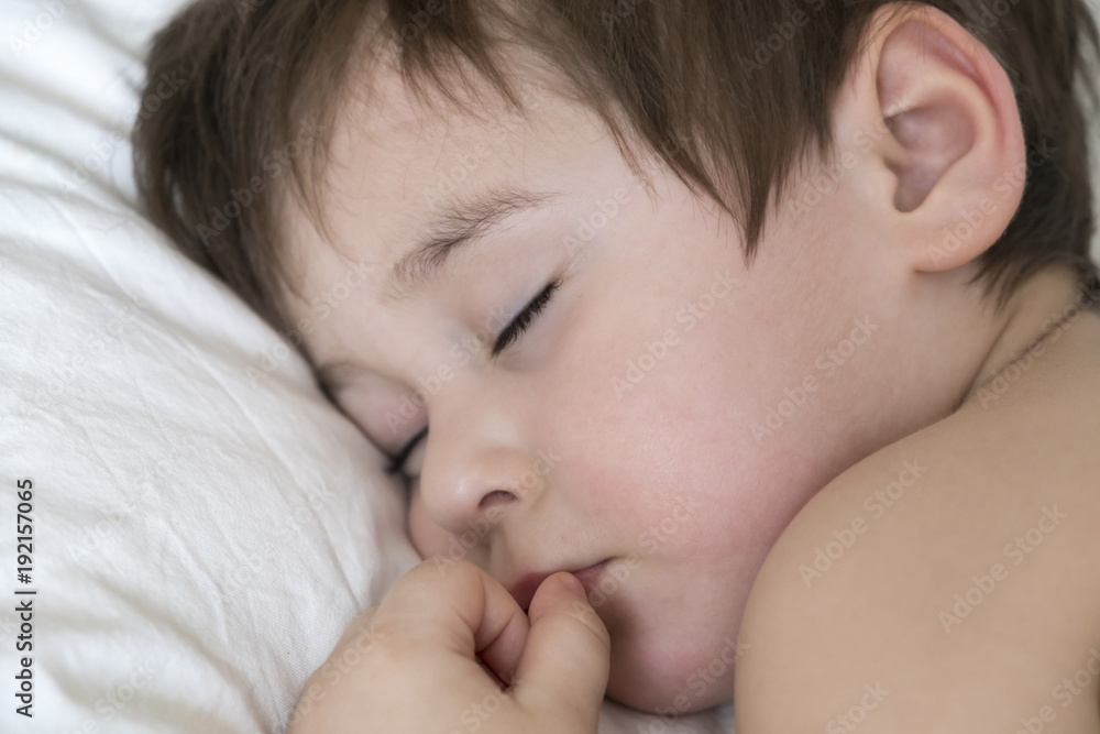 Peaceful baby lying on a bed while sleeping in a bright room. cute two year old Asian boy on white the pillow Peaceful baby lying on a bed while sleeping in a bright room. cute two year old Asian boy on white the pillow