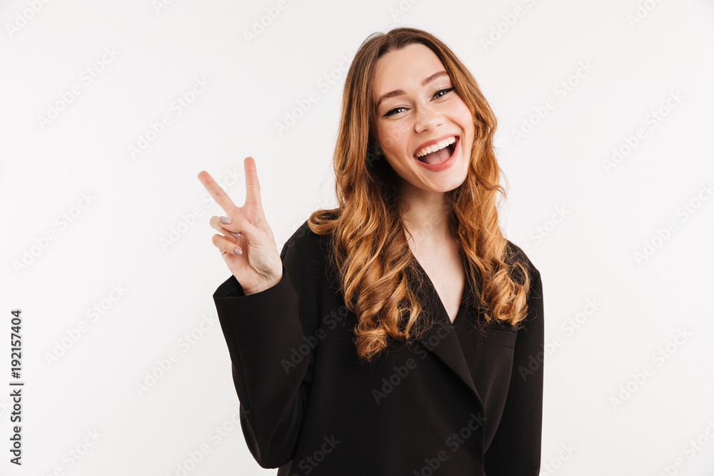 Picture of happy woman 20s with long auburn hair in black jacket posing on camera and showing peace or victory sign, isolated over white background Picture of happy woman 20s with long auburn hair in black jacket posing on camera and showing peace or victory sign, isolated over white background