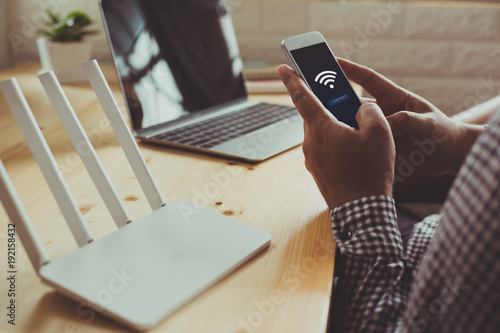 closeup of a wifi router and a man using smartphone on living room at home ofiice photo