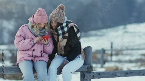 attractive girls women female holding looking smartphone screen amazed excited glad emotional face calm scrolling touchscreen pointing finger internet surfing social networking winter village tourism photo