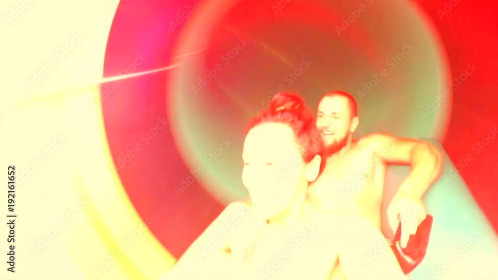 Young Mixed Race Couple Having Fun Riding Down in a Water Slide Tube and Making Selfie with Gopro Camera. HD. Young Mixed Race Couple Having Fun Riding Down in a Water Slide Tube and Making Selfie with Gopro Camera. HD.