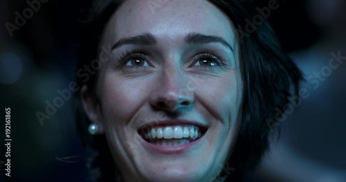 A young woman at the movies begins to smile and laugh