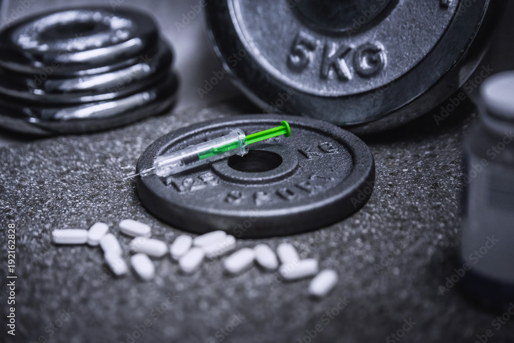 bottle of doping drug and syringe are put in the black ground in gym bottle of doping drug and syringe are put in the black ground in gym