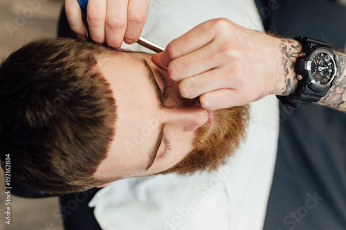 Close up image of barber makes beard cut of a man