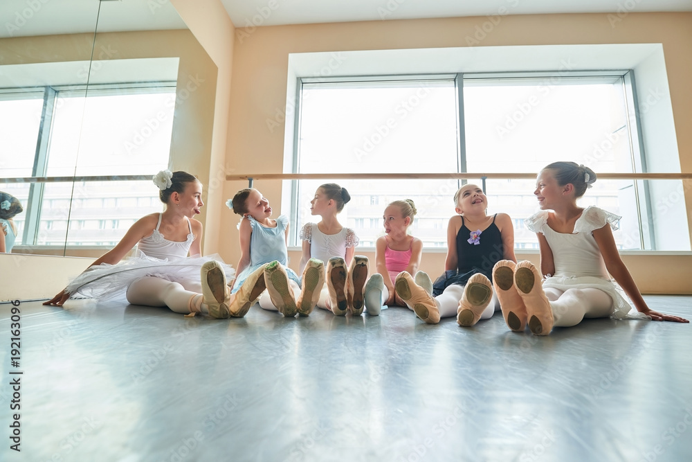 Fototapeta premium Cute ballerinas having fun in studio. Six young ballerinas showing tongues to each other and laughing. They are good friend.