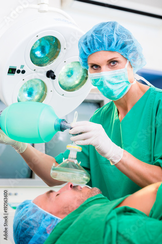 Surgeon with anesthetic mask in operating room of hospital