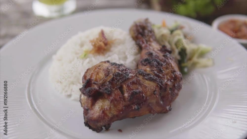 Grilled chicken leg with steamed rice at the restaurant. Plate with chicken, rice served on the wooden table with healthy salad Grilled chicken leg with steamed rice at the restaurant. Plate with chicken, rice served on the wooden table with healthy salad