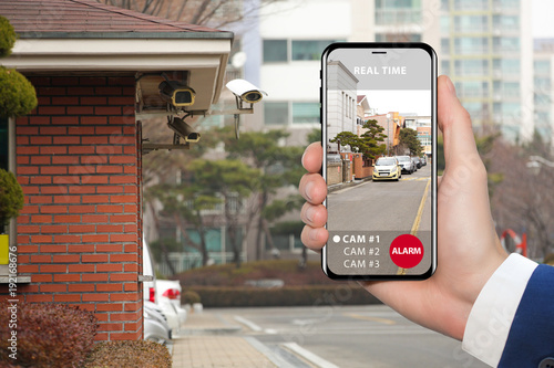 Hand with phone. On the screen interface of remote control surveillance camera