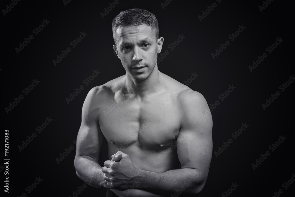 Portrait of a shirtless athletic guy, black background