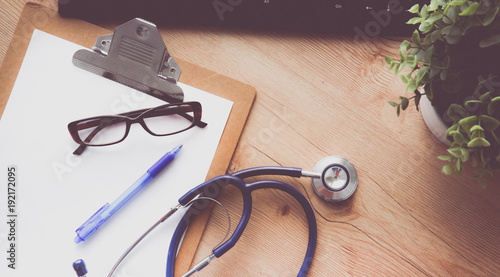 A medical stethoscope near a laptop on a wooden table, on white