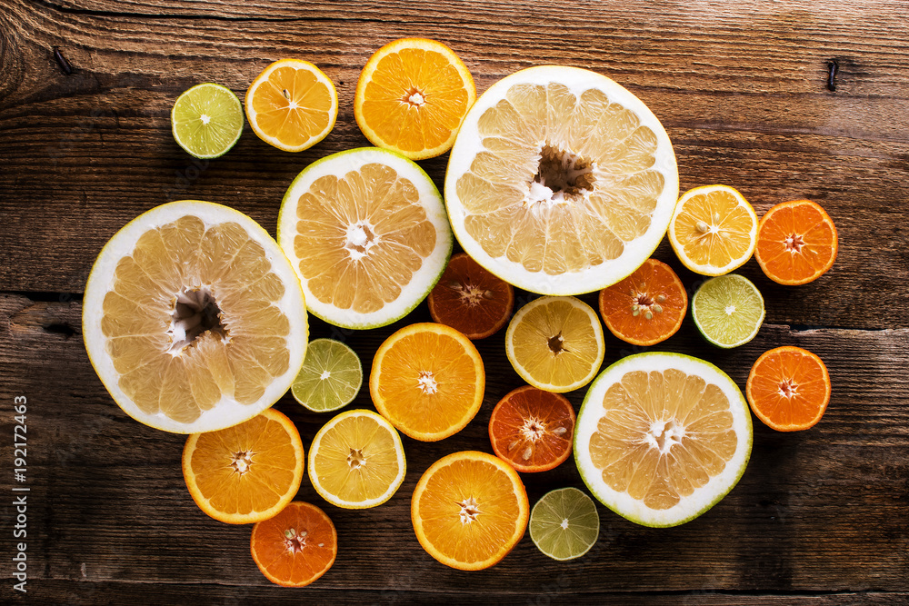 colorful citrus fruits, cut in half, on a dark old board colorful citrus fruits, cut in half, on a dark old board