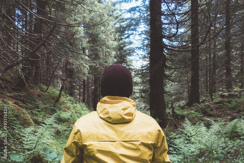 Man in yellow jaket in wild forest. Travel and adventure concept. Mountains landscape photography