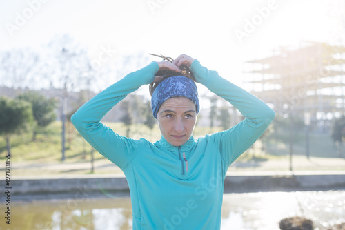 Sport woman tying ponytail in the park