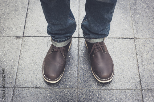 man wearing blue jeans and a leather boots standing on brick floor, vintage color concept.