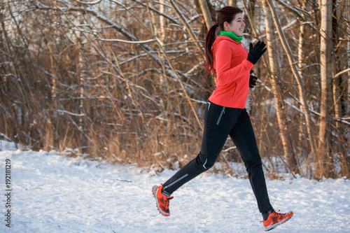 Image of woman in sports uniform on morning run in winter forest