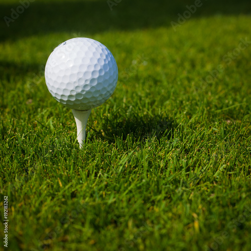 Golf ball on a tee against the golf course with copy space