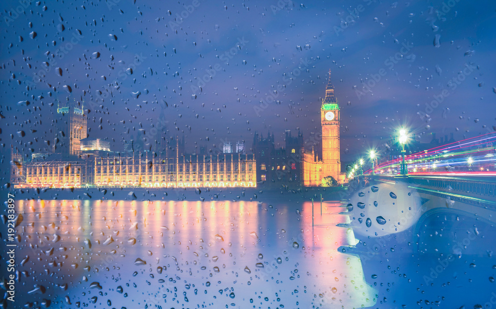 Big Ben view through the window with raindrops at night, London, UK.