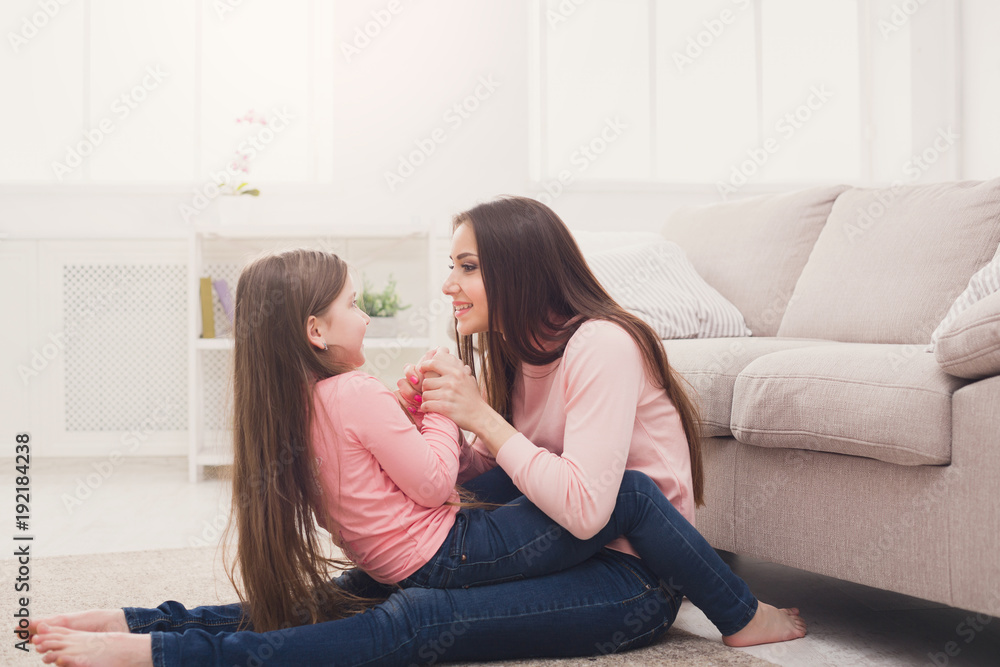 Mother with her cute daughter having fun in the bedroom.