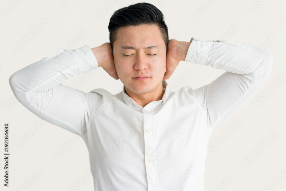 Stressed Asian man annoyed with noise Stressed Asian man annoyed with noise