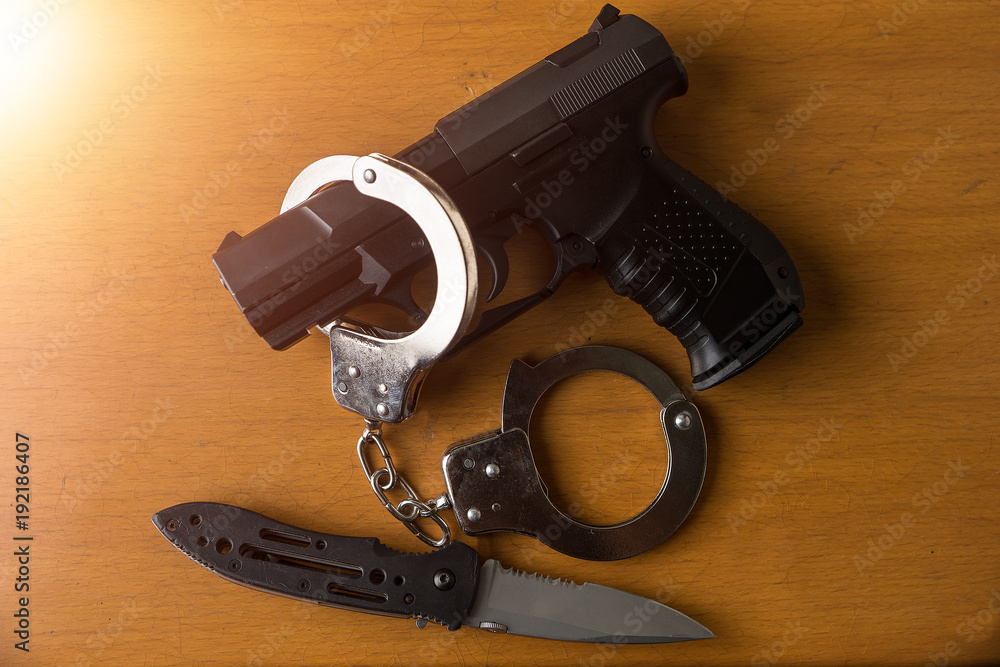Tactical gear set of Pistol gun knife handcuff and clock on wooden background. Police or military equipment concept.