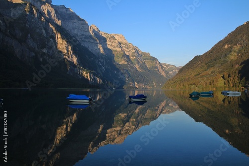 Summer morning at lake Klontalersee. Mountain range Glarnisch reflecting in the water. photo