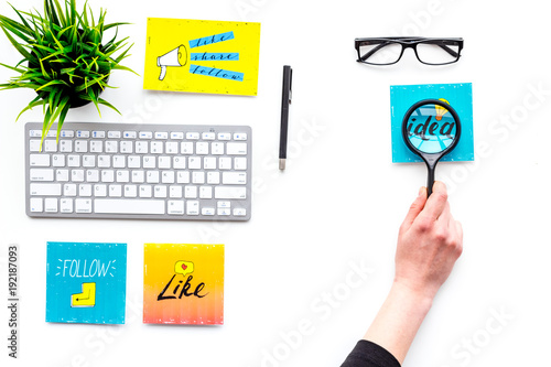 Digital marketing. Work desk of marketing specialist with social media icons and symbols. Hand with magnifiger on white background top view copy space photo