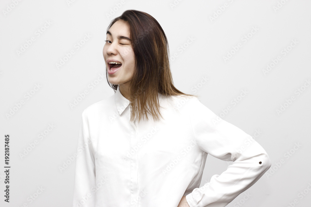 Indoor portrait of young beautiful charming woman winking dressed in formal white shirt. Facial expressions, emotions, lifestyle concept Indoor portrait of young beautiful charming woman winking dressed in formal white shirt. Facial expressions, emotions, lifestyle concept