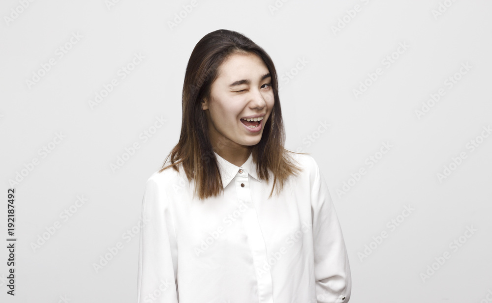 Indoor portrait of young attractive charming woman winking dressed in formal white shirt. Facial expressions, emotions, lifestyle concept Indoor portrait of young attractive charming woman winking dressed in formal white shirt. Facial expressions, emotions, lifestyle concept