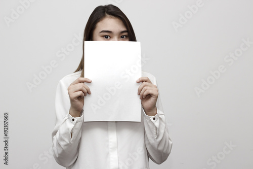 Young girl holding empty blank white board on her face. Leaflet presentation. Pamphlet hold hands. Girl show clear offset paper. Sheet template.