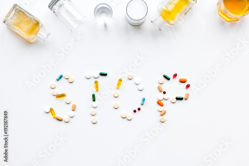 Stop alcohol. Word stop lined with pills near glasses and bottles on white background top view © 9dreamstudio