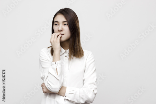 Indoor portrait of young attractive tricky woman thinking, getting nervous and biting her nails. Negative stressed facial expressions, emotions and feelings concept