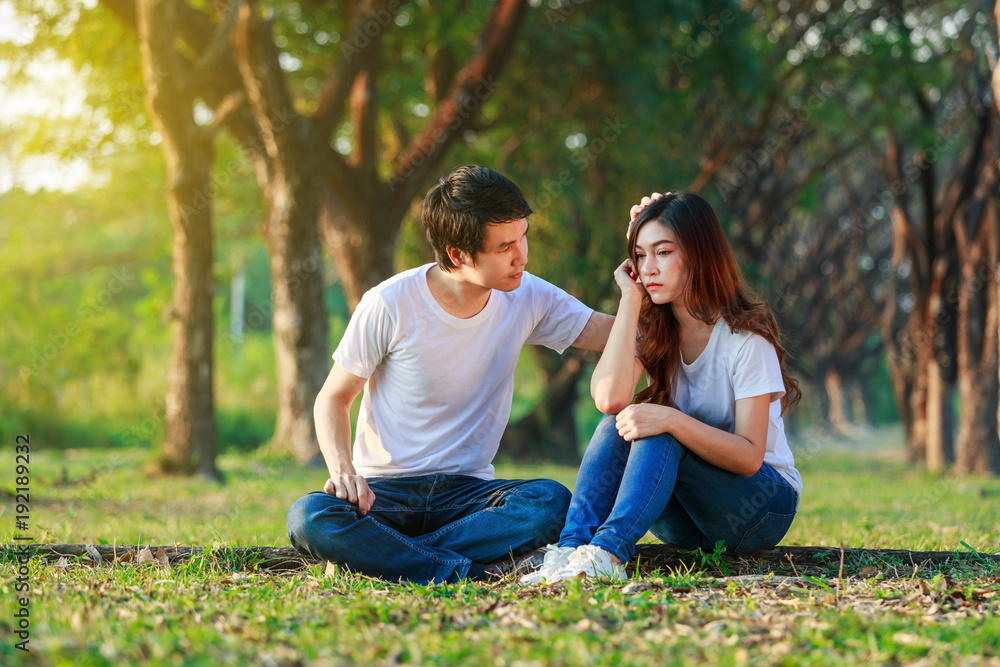 unhappy woman sitting with a concerned guy comforting her in park unhappy woman sitting with a concerned guy comforting her in park
