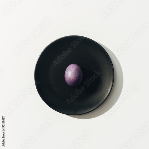 top view of purple easter egg on black plate, on white
