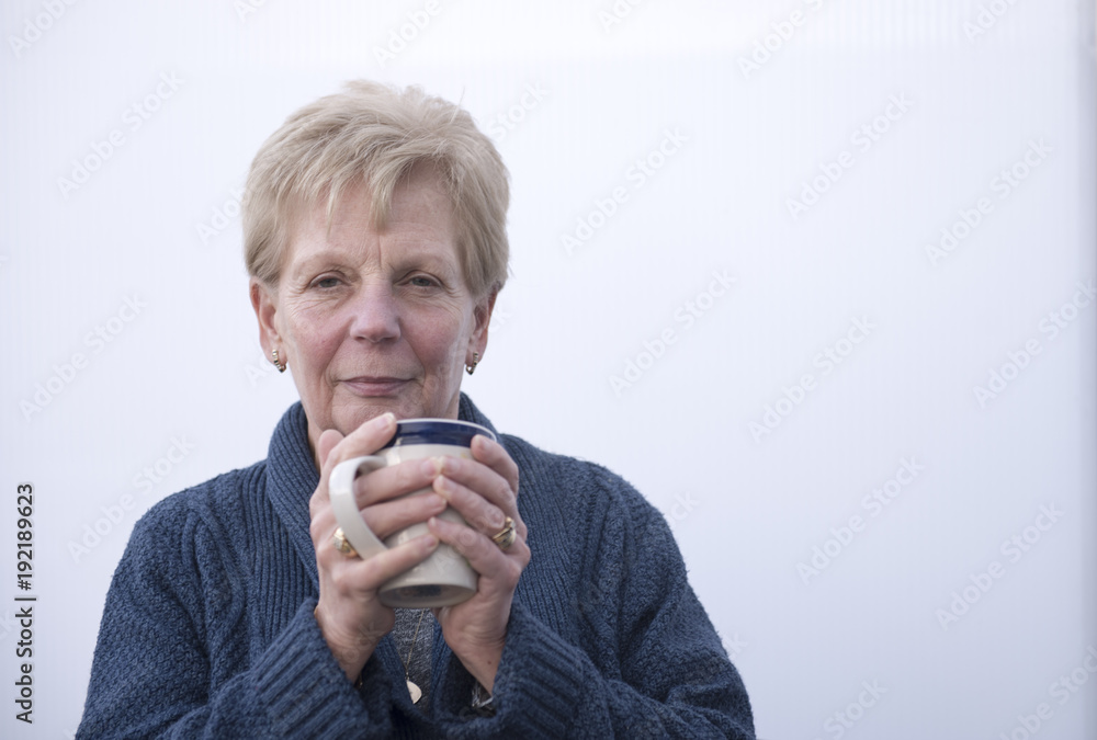 Mature woman holding a cup of coffee, with copy space Mature woman holding a cup of coffee, with copy space