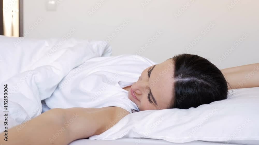 Nude woman hugging a white blanket and looking straight Nude woman hugging a white blanket and looking straight
