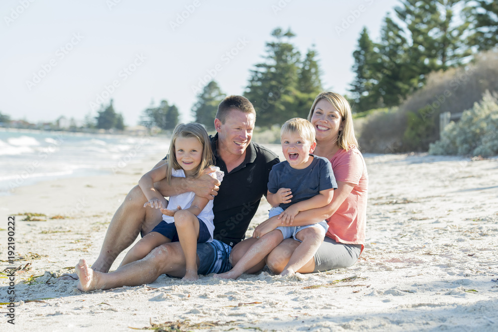 happy beautiful Caucasian family having holidays on the beach smiling with mother and father sitting on sand with little son and young daughter happy beautiful Caucasian family having holidays on the beach smiling with mother and father sitting on sand with little son and young daughter