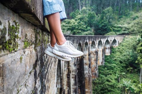 Woman sits on the Demodara nine arches bridge in Ella, Sri Lanka: close up feet image photo