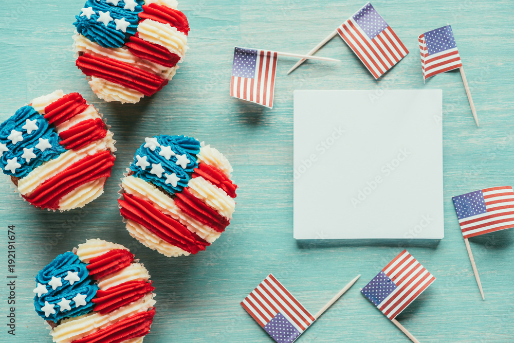 Obraz premium flat lay with arranged cupcakes and american flags on wooden tabletop, presidents day celebration concept
