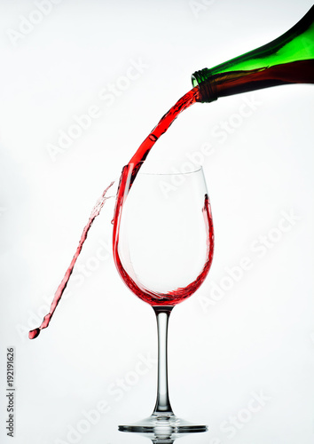 Pouring red wine in glass goblet isolated on white