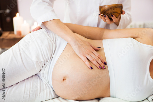 Young pregnant woman having abdominal massage at beauty spa salon. Close-up.  Spa treatment