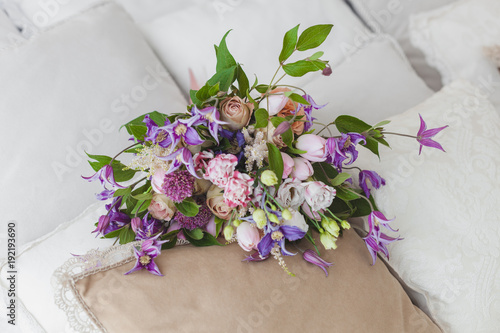 Fresh bouquet of flowers lies on the bed in the morning.