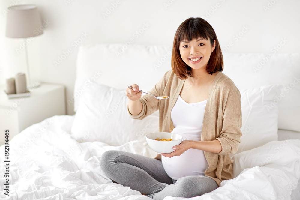 happy pregnant woman eating cereal flakes at home happy pregnant woman eating cereal flakes at home