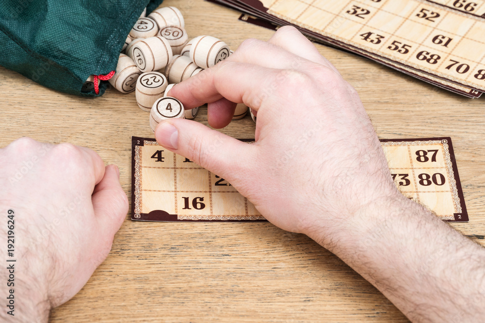 Fototapeta premium Male hands play in the lotto close the fallen figure on the card, close-up