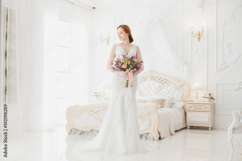 Bride in the wedding dress is standing in the royal bedroom, she is waiting for her fiance. Bride in the wedding dress is standing in the royal bedroom, she is waiting for her fiance.